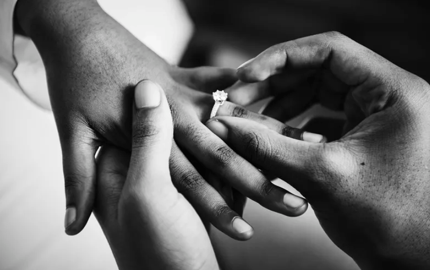 Man putting on ring on woman's finger