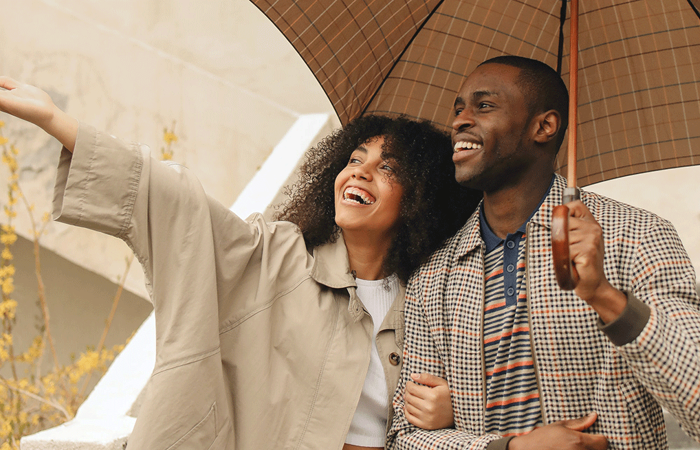 couple smiling holding an umbrella